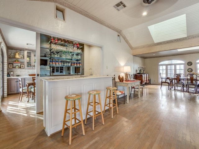 bar with lofted ceiling and light wood-type flooring