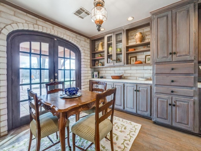 dining area featuring french doors, brick wall, and light hardwood / wood-style floors