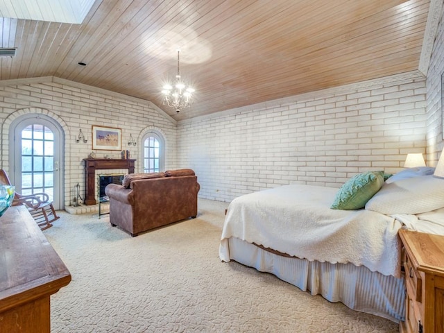 carpeted bedroom featuring vaulted ceiling, a fireplace, brick wall, and an inviting chandelier