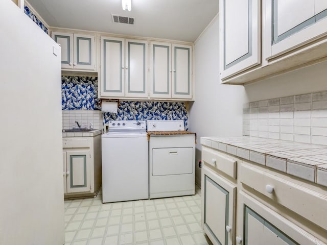 washroom with washer and dryer, cabinets, and sink