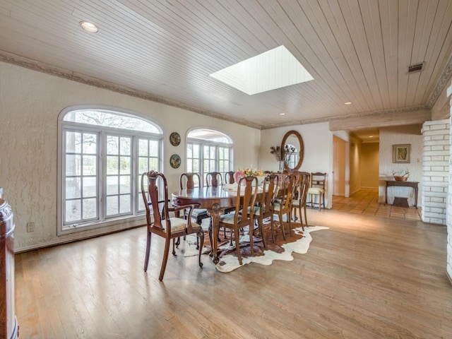 dining area with light hardwood / wood-style flooring, a skylight, and wooden ceiling