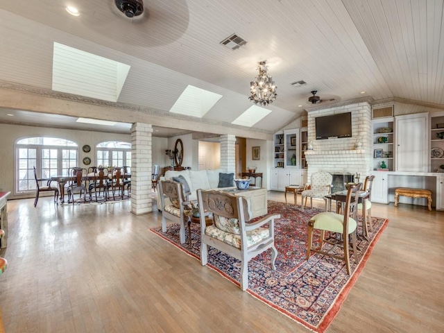 living room with ceiling fan with notable chandelier, wood ceiling, ornate columns, light hardwood / wood-style floors, and built in features