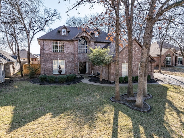 french provincial home featuring a front yard, brick siding, and fence