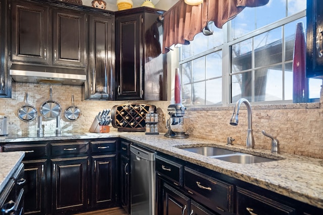 kitchen with under cabinet range hood, a sink, backsplash, light stone countertops, and dishwasher