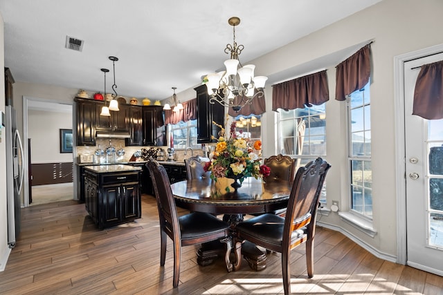 dining room featuring a chandelier, visible vents, and light wood-style flooring