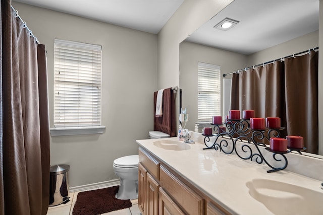 full bathroom featuring toilet, double vanity, a sink, and tile patterned floors