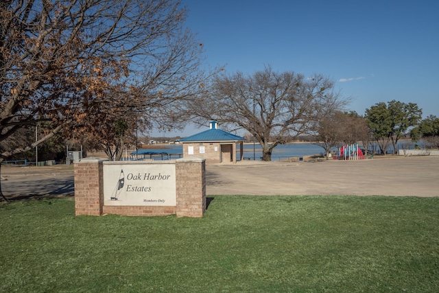 view of home's community featuring playground community, a lawn, and a water view