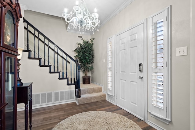 foyer featuring ornamental molding, a notable chandelier, dark wood finished floors, and stairway