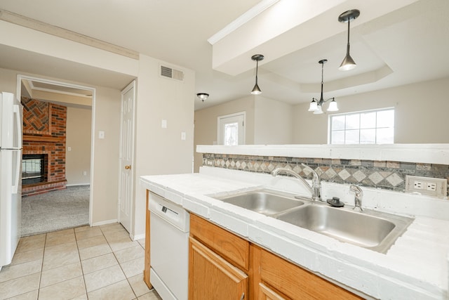 kitchen featuring pendant lighting, white appliances, a fireplace, decorative backsplash, and a raised ceiling