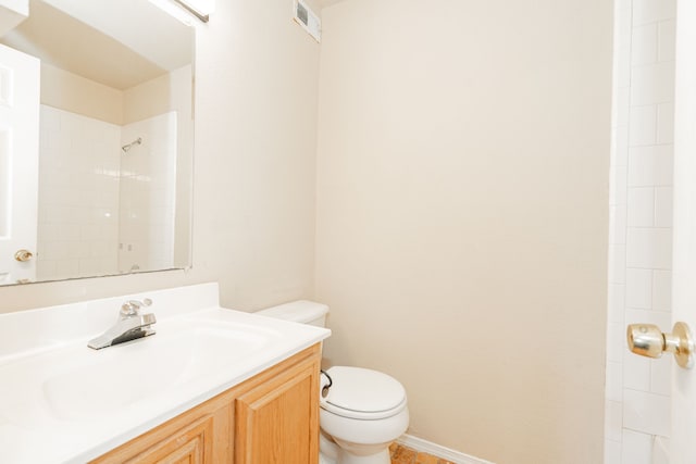 bathroom with toilet, vanity, and a tile shower