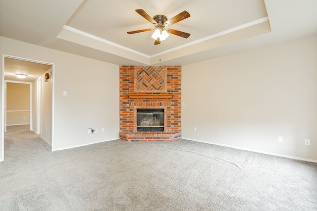 unfurnished living room featuring a raised ceiling, carpet, ceiling fan, and a fireplace