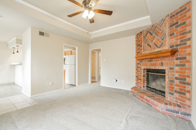 unfurnished living room with carpet floors, a fireplace, a raised ceiling, ornamental molding, and ceiling fan