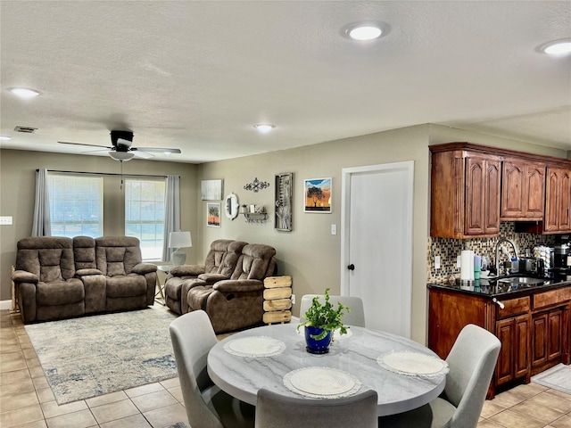 dining space with a textured ceiling, light tile patterned flooring, visible vents, and a ceiling fan