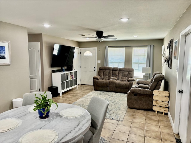 living area with a ceiling fan, visible vents, and baseboards