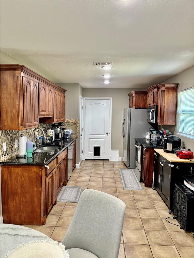 kitchen featuring light tile patterned floors, stainless steel appliances, a sink, and visible vents