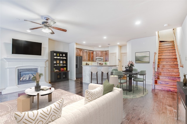 living room with ceiling fan and dark wood-type flooring