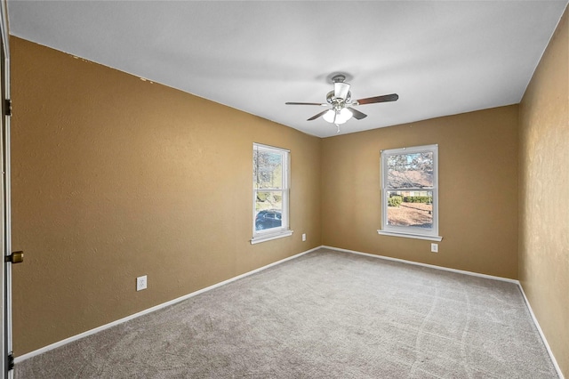 carpeted empty room with ceiling fan and plenty of natural light