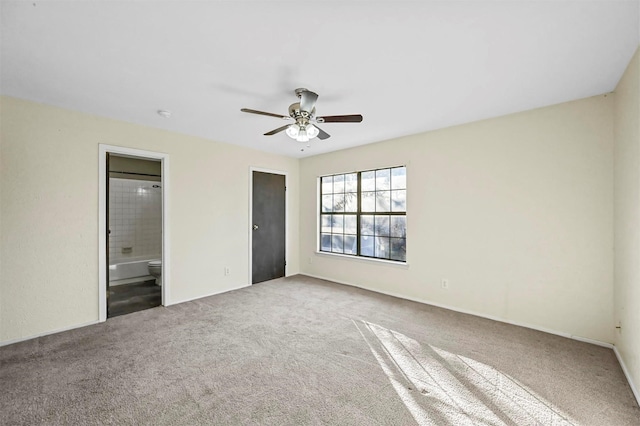 unfurnished bedroom featuring ceiling fan, carpet floors, and ensuite bath