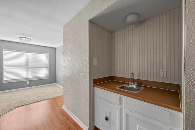 bar with sink, white cabinetry, and light hardwood / wood-style flooring