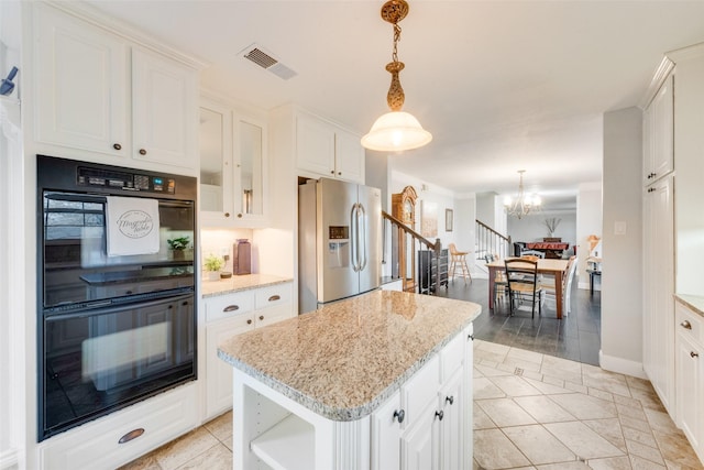 kitchen with black double oven, white cabinets, stainless steel fridge, and a center island