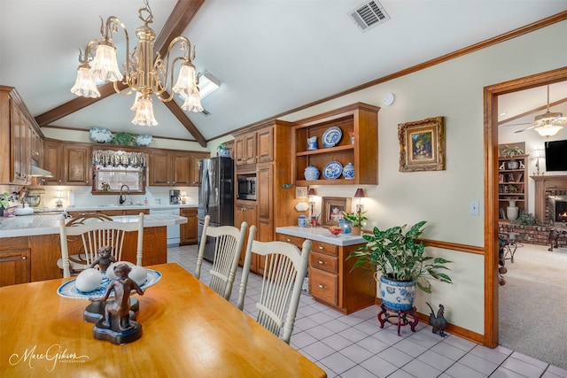 dining space featuring a fireplace, vaulted ceiling with beams, sink, light tile patterned flooring, and ornamental molding