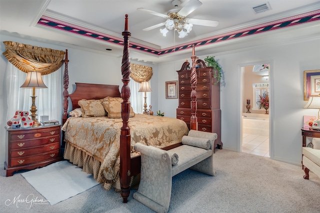 bedroom featuring ceiling fan, light colored carpet, a tray ceiling, connected bathroom, and ornamental molding