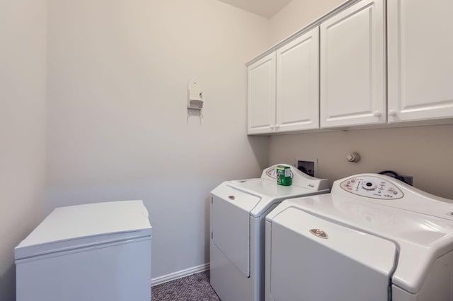 washroom with cabinets, washer and dryer, and dark tile patterned flooring