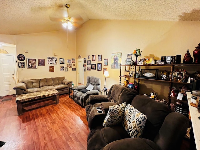 living room with ceiling fan, vaulted ceiling, a textured ceiling, and hardwood / wood-style flooring