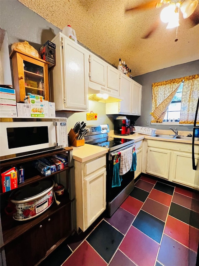 kitchen with ceiling fan, electric range, sink, a textured ceiling, and white cabinets