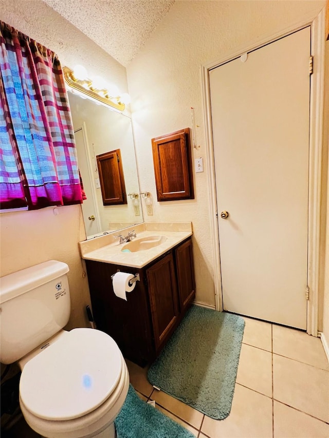 bathroom featuring a textured ceiling, toilet, tile patterned flooring, and vanity