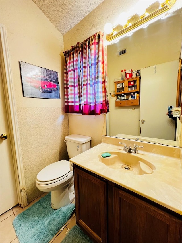 bathroom featuring toilet, vanity, tile patterned floors, and a textured ceiling