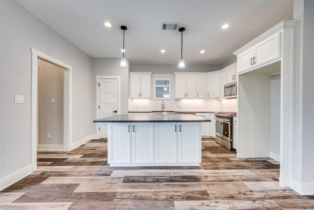 kitchen with white cabinets, a kitchen island, stainless steel appliances, and pendant lighting