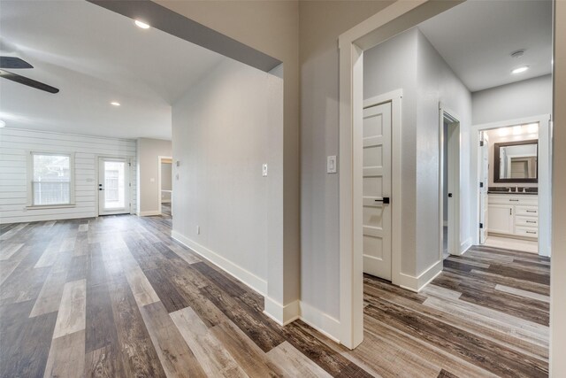 spare room featuring ceiling fan, wood-type flooring, plenty of natural light, and wood walls