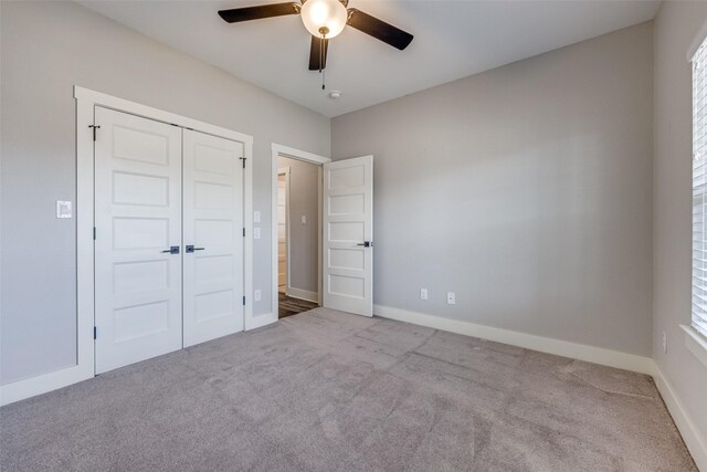 unfurnished bedroom with ceiling fan, a closet, and light carpet