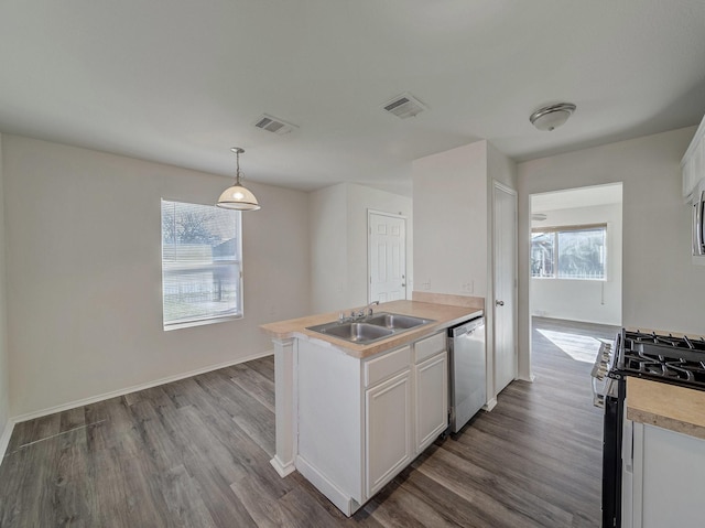 kitchen with pendant lighting, white cabinets, appliances with stainless steel finishes, wood-type flooring, and sink