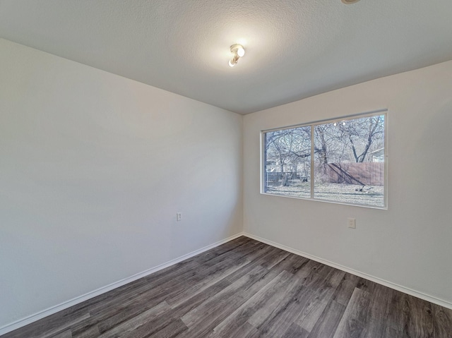 unfurnished room with dark wood-type flooring and a textured ceiling