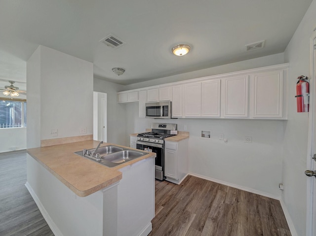 kitchen with kitchen peninsula, sink, white cabinetry, appliances with stainless steel finishes, and a kitchen breakfast bar