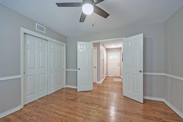 unfurnished bedroom with ceiling fan, light wood-type flooring, and a closet