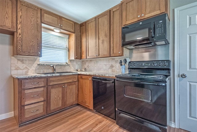 kitchen with sink, decorative backsplash, light wood-type flooring, and black appliances