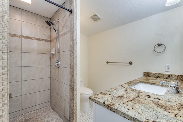 bathroom with toilet, vanity, and tiled shower