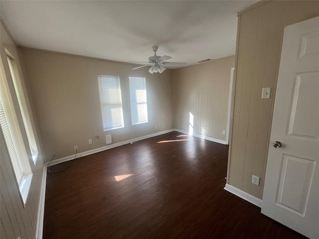 unfurnished room with ceiling fan, wood walls, dark hardwood / wood-style flooring, and ornamental molding