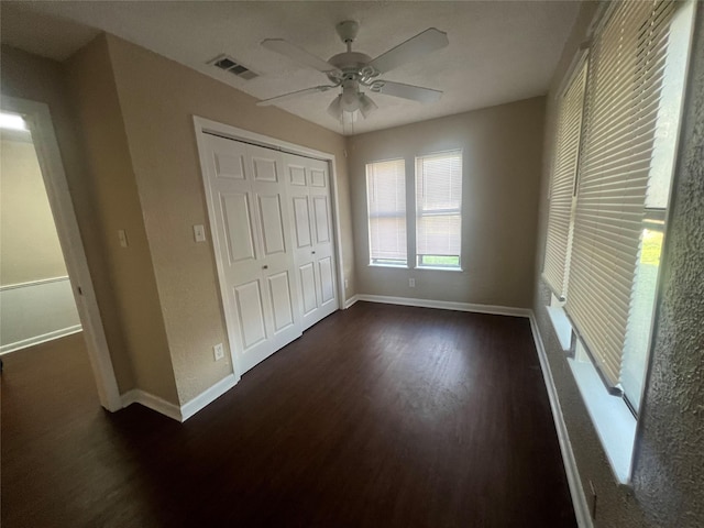 unfurnished bedroom with ceiling fan, a closet, and dark hardwood / wood-style flooring