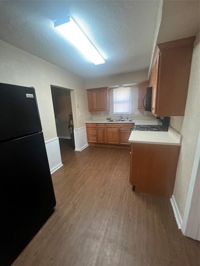 kitchen featuring black appliances, sink, a textured ceiling, and hardwood / wood-style floors