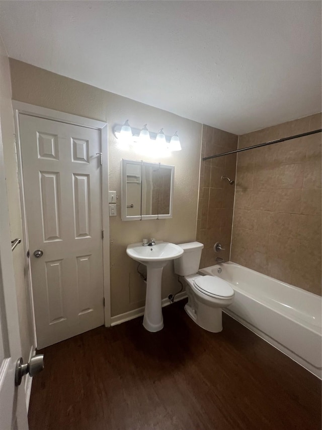 full bathroom with toilet, tiled shower / bath combo, wood-type flooring, and sink