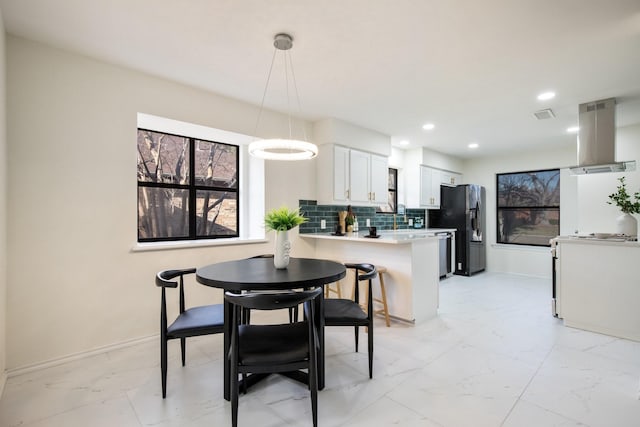 kitchen with decorative light fixtures, kitchen peninsula, black refrigerator with ice dispenser, white cabinetry, and island range hood