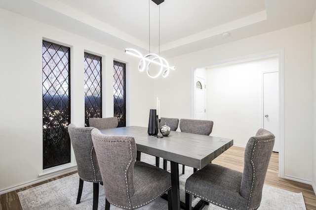 dining space featuring a tray ceiling, a chandelier, and hardwood / wood-style flooring