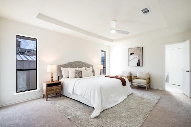 bedroom with light carpet, ceiling fan, and a raised ceiling