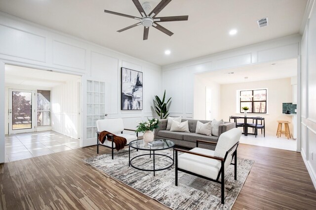 living room featuring ceiling fan, crown molding, french doors, and a brick fireplace