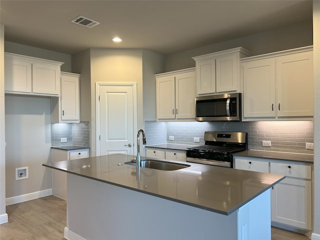 kitchen featuring white cabinets, appliances with stainless steel finishes, and a center island with sink