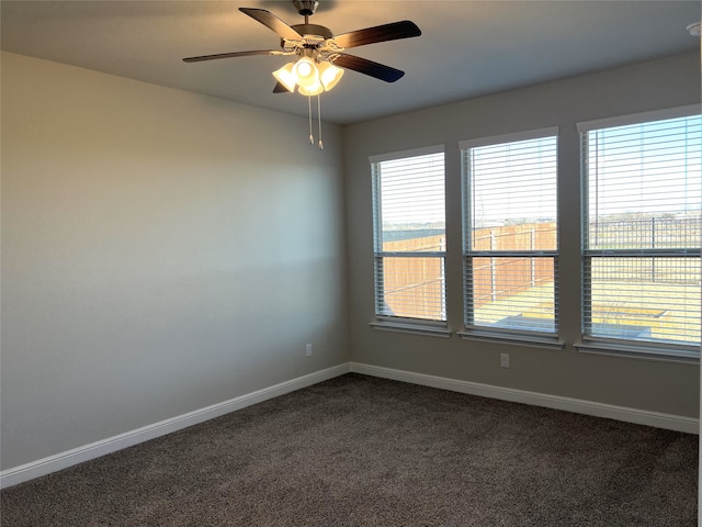 unfurnished room with ceiling fan and dark carpet